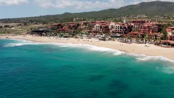 Aerial, tracking, tilting towards waves, hitting the Sheraton beach, in Cabo — Stock Video