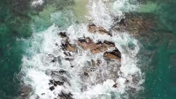 Πάνω προς τα κάτω Ανερχόμενη Αεροφωτογραφία των κυμάτων που συγκρούονται σε βράχους από την αμμώδη παραλία — Αρχείο Βίντεο