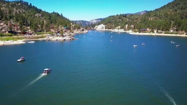 Aérea, volando sobre el lago Big Bear sobre el agua pasando barcos, coches en la carretera — Vídeo de stock