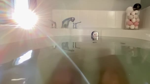 Masculin relaxare în cadă de baie cu apus de soare prin fereastra băii — Videoclip de stoc