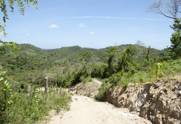 背景是一条尘土飞扬的道路和多山的罗坦岛景观 洪都拉斯 — 图库照片