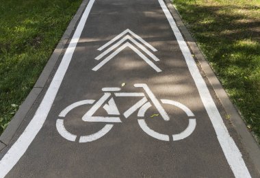 Şehir parkında asfalt yolda bir bisiklet ve bir ok çiziliyor..