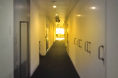 Birçok beyaz kapalı kapı ile uzun koridor perspektif içine bakarak sonunda aydınlatma, bulanık arkaplan