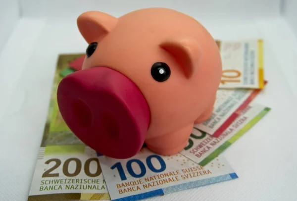 Pink piggy bank with swiss money and currency of switzerland. Swiss francs. Money in Switzerland