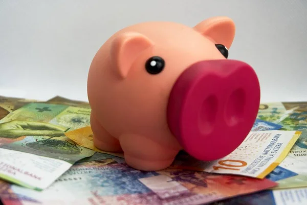 Pink piggy bank with swiss money and currency of switzerland. Swiss francs. Money in Switzerland