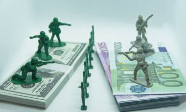 İki destenin üzerinde minyatür plastik asker figürü, biri dolar banknotlarından, diğeri de ortasında plastik bir hendek olan avro.