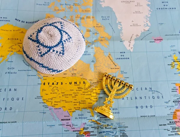 Photo of a north american map with a jewish yarmulke and a chandelier menorah. Jewish America