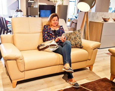 Akıllı telefonları kullanırken bir odada kanepede oturan kadın.