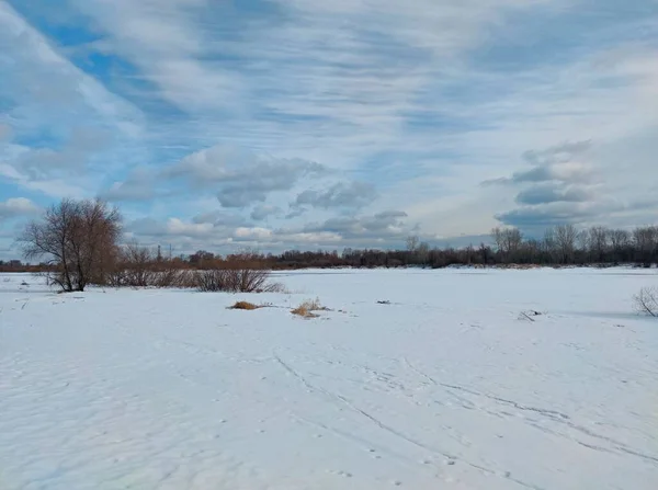 冬の冬眠後まだ溶けていない川と春の風景珍しい雲と信じられないほど美しい青空に対するフィールドのように見えます — ストック写真