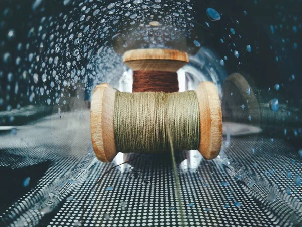 two old spools of thread in a dark glass tunnel with water droplets in a creative macro photo