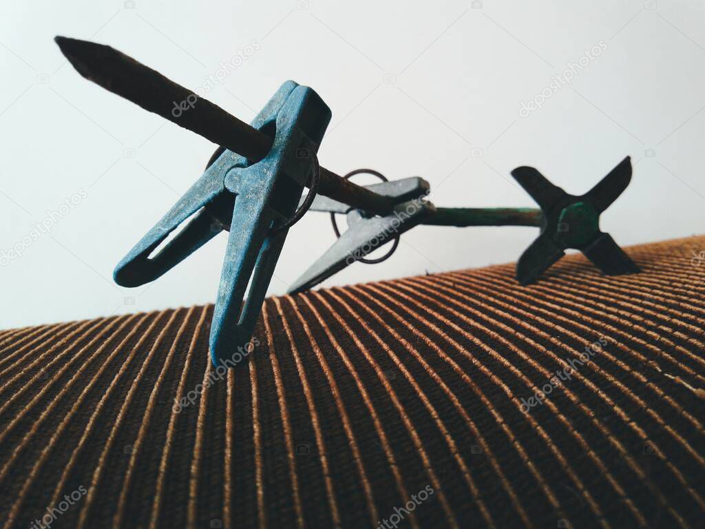 an old large nail with a meat grinder knife in the form of a hat and old clothespins attached to it in an abstract and creative macro photo