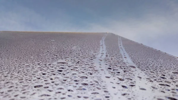 wet footprints resembling a road on a glass surface covered with water droplets against a blue sky in a creative photo