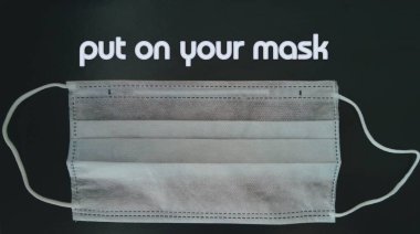 Siyah arka planda tıbbi maske ve maskenize yazılan yazı