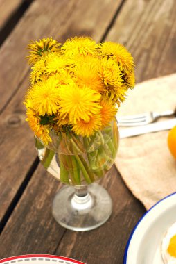 Tahta bir masanın üzerinde bir buket karahindiba