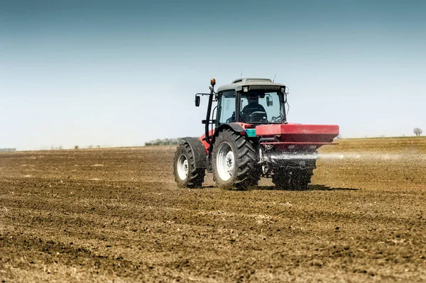 Tractor spreading artificial fertilizers in field — Stock Photo, Image