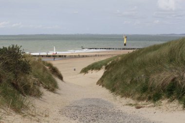 Cadzand 'daki Hollanda sahillerindeki kum tepelerinden geçen bir hendek. Dalgalar, dalgalar ve deniz feneriyle batılı denizi çok güzel görüyor. 