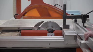 Bir işçi elektrikli testereyle tahtanın bir parçasını testereyle kesiyor.