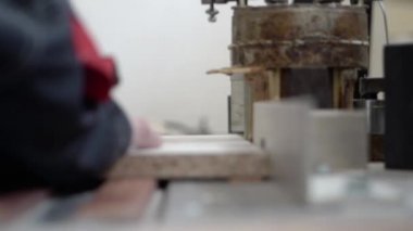 Marangoz tahtanın bir parçasını özel bir makineye yapıştırıyor. Yakın plan..