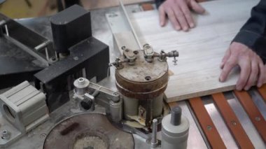 Marangoz tahtanın bir parçasını özel bir makineye yapıştırıyor. Yakın plan..