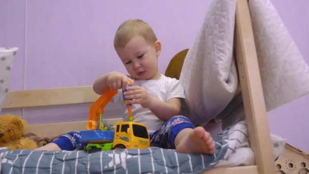 Okouzlující Dítě Sedí Posteli Kroutí Otáčí Šrouby Autíčku — Stock video