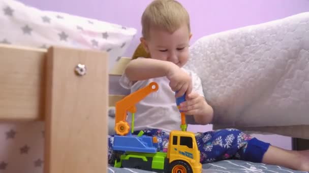 Charming Baby Sits Bed Twists Turns Bolts Toy Car — Stock Video