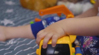 Çekici bebek yatakta oturur ve cıvataları çevirir oyuncak bir arabada.