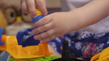 Çekici bebek yatakta oturur ve cıvataları çevirir oyuncak bir arabada.