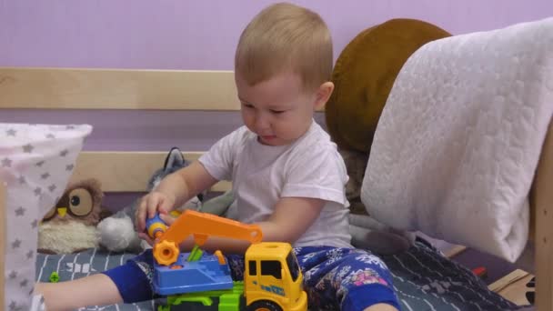 Urocze Dziecko Siedzi Łóżku Skręca Śruby Zabawkowym Samochodzie — Wideo stockowe