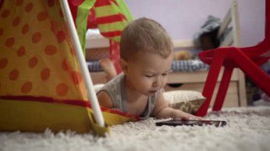 Sevimli bebek çocuk çadırında telefonla oynuyor. Video ve resim izliyor..