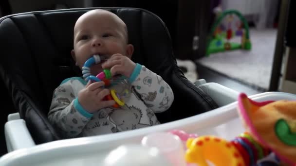 아기가 유아용 의자에 앉아서 장난감을 — 비디오