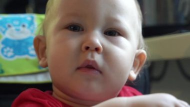 Çekici bir bebek kameraya dikkatlice bakar ve sonra komik bir şekilde güler..