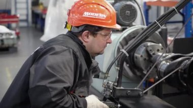 Magadan, Rusya - 15 Ağustos 2019. Ağır ekipmanlar için motor ve şanzıman yenileme fabrikası. Kasklı bir işçi özel bir makinenin arkasında çalışır..