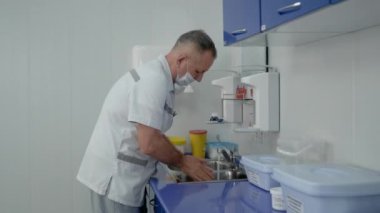 Yetişkin bir adam - bandajlı bir doktor ellerini lavaboda iyice yıkıyor..
