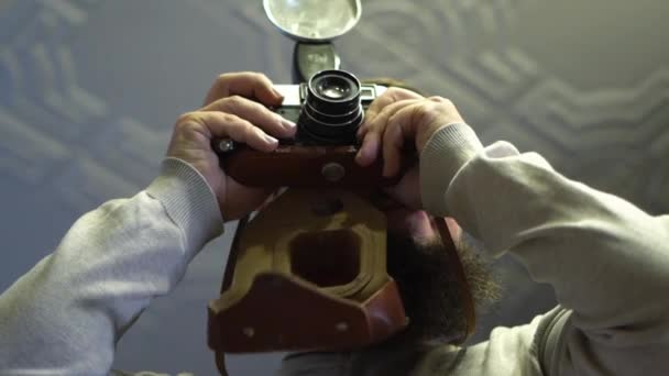 Joven Barbudo Usa Una Cámara Vintage Mirando Viejas Fotos Cámara — Vídeo de stock