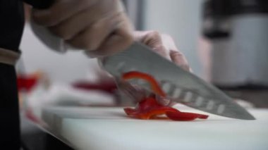 Aşçı mutfak masasında kırmızı biber keser. Yakın plan..