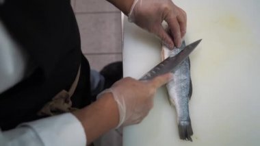 Aşçı balığa kesikler atar. Tuzlayıp biber ekecek..