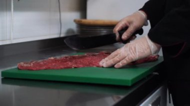 Aşçı yeşil bir kesme tahtasında et keser. Biftek yapacak..