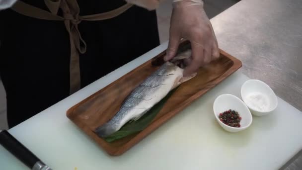 厨师给鱼打气和打辣椒 它躺在厨房桌子上 旁边有调味品 — 图库视频影像