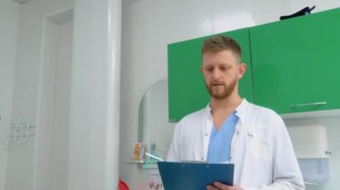 Tıbbi giysili genç bir doktor, hastanın tıbbi kayıtlarını güzel bir hemşireyle tartışıyor..