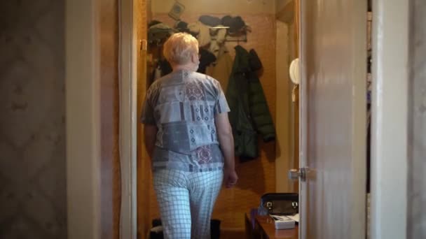 おばあちゃんはドアのピープルを見ている 彼女はCovid 19コロナウイルスパンデミックのボランティアを待っています — ストック動画