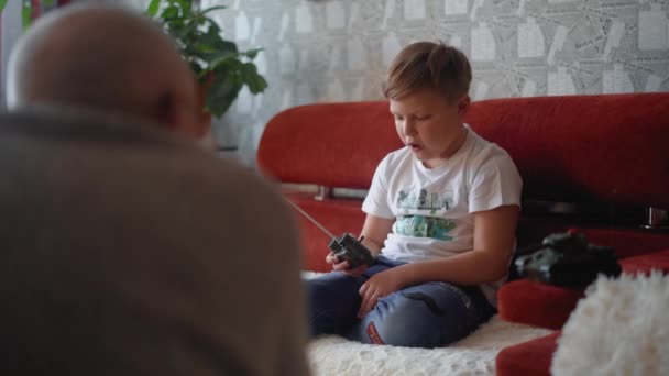Bedstefar Taler Med Sit Barnebarn Læser Bog Barnebarnet Holder Fjernbetjeningen – Stock-video