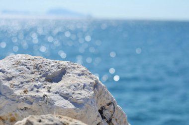 Mavi deniz zemininde beyaz kumsal taşı. Yaklaşma taşı ve bulanık deniz..