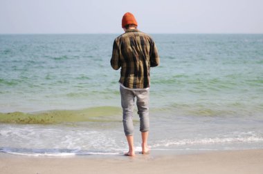 Bir adam sırtı denize dönük durur. Okyanus manzarası. Denizde dinlenen adam.