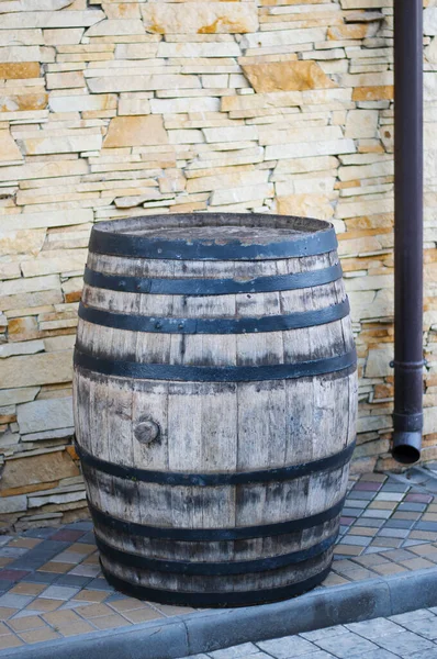 Old wooden barrel with black iron rings left on the stone street. Old fashioned antique whiskey wood barrel or wine cask.