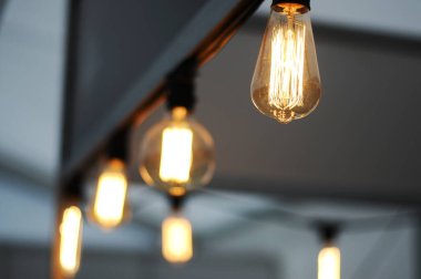 Modern bir kafede parlak lambalar, bulanık arka plan, Edison Lambası, iç ve tasarım için lambalar, bir kafede sarı iplik lambaları, yakın plan.