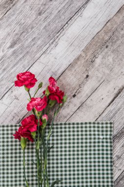 Yeşil peçetedeki kırmızı karanfil çiçekleri