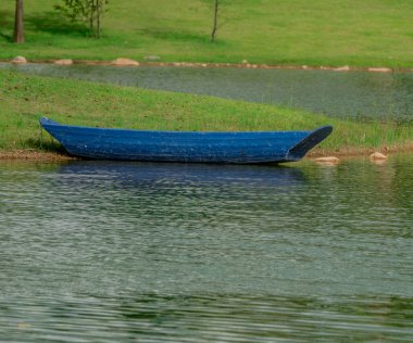 Eski mavi tekne huzurlu sularla dolu boş bir göl kıyısında bir gezi bekliyor.