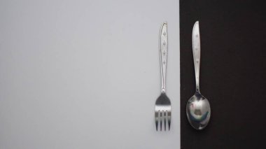 Fotoğrafta görülen çatal bıçak seti siyah beyaz arka planı olan bir çatal bıçak takımı ve bir plaka içeriyordu.