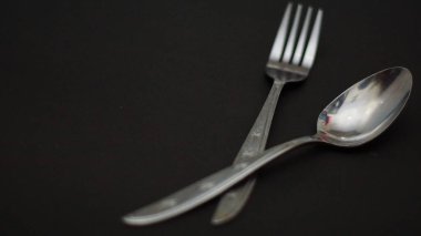 Fotoğrafta görülen çatal bıçak seti siyah beyaz arka planı olan bir çatal bıçak takımı ve bir plaka içeriyordu.