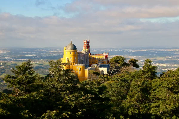 Palacio Da Pena Koruluğun arkasında ve bulutlu bir gökyüzünün altında.